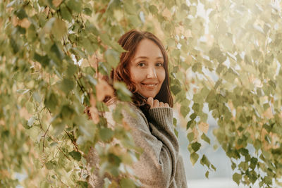 Portrait of smiling woman standing by tree branches