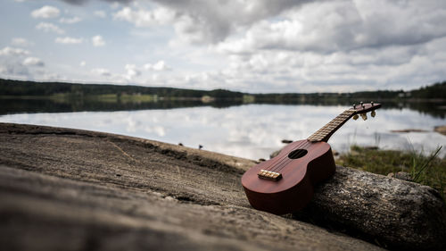 View of guitar on lake against cloudy sky