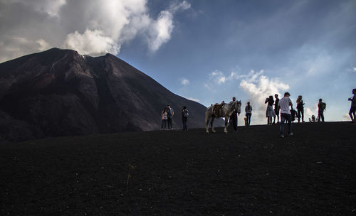 People on mountain against cloudy sky