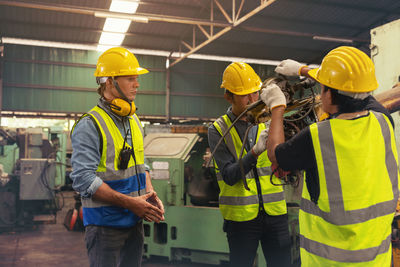 Engineers in an industry plant setting up machines vs a background of a machine factory.