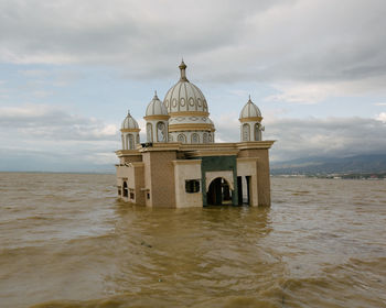 View of building by sea against cloudy sky