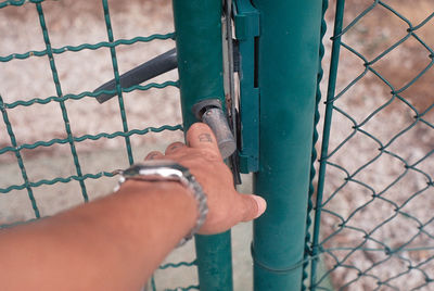 Close-up of hand holding chainlink fence