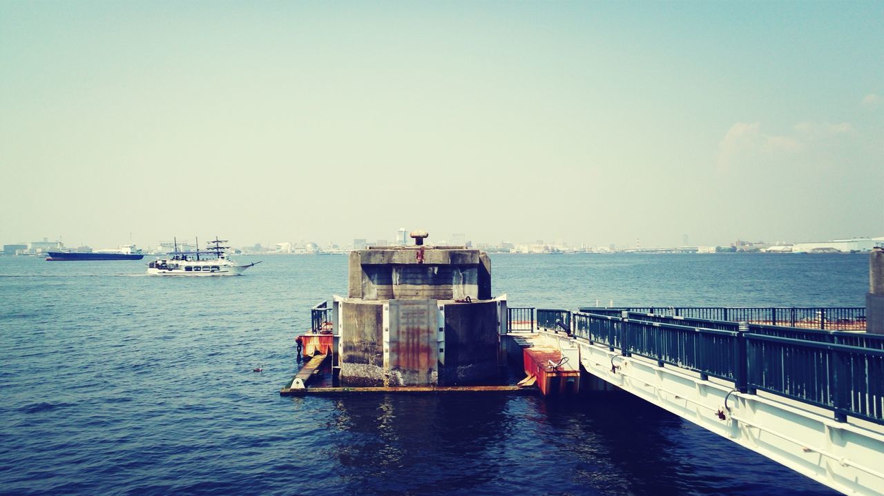 water, nautical vessel, sea, transportation, waterfront, mode of transport, boat, copy space, built structure, clear sky, blue, rippled, architecture, sky, building exterior, horizon over water, pier, nature, day, tranquility