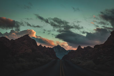 Scenic view of road amidst mountains against sky during sunset