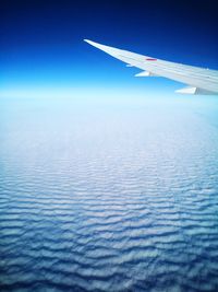 Aerial view of airplane wing against blue sky