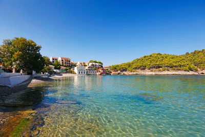 Scenic view of sea by buildings against clear blue sky