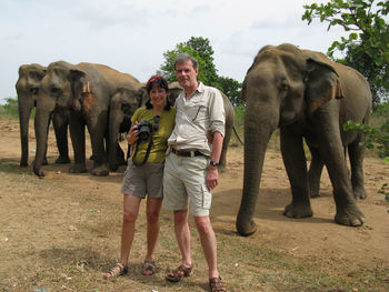 Full length of portrait of couple standing by elephant