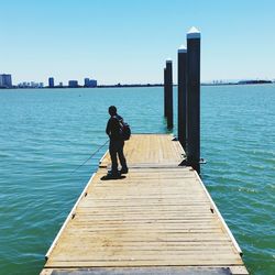 Full length of man fishing by turquoise sea