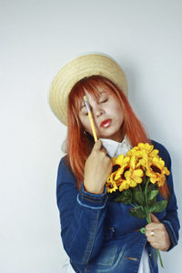 Woman in hat holding flowers against white background