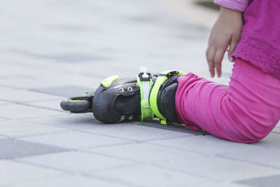 Low section of girl kneeling with skating on footpath