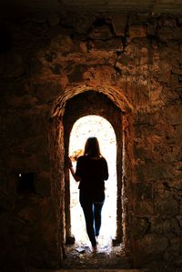 Rear view of woman standing in tunnel