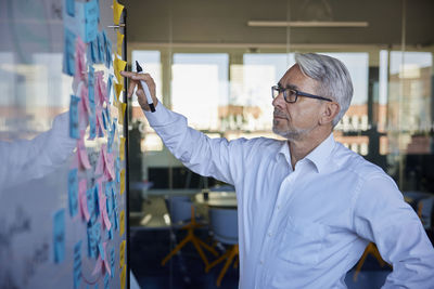 Businessman planning strategy on sticky notes in office