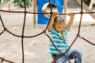 Low angle view of girl playing on rope in playground