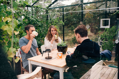 Young men and woman having coffee at table in glass cabin