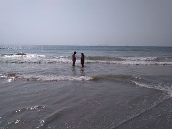 People on beach against clear sky