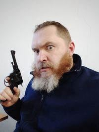 Portrait of man holding camera over white background