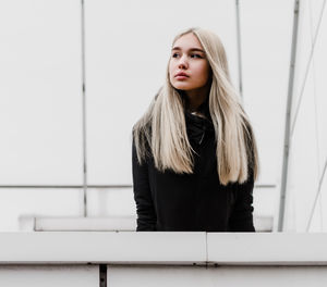 Portrait of a beautiful young woman standing against wall