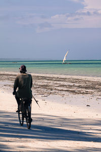 Rear view of man riding bicycle at beach