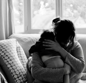 Mother holding her baby son in living room