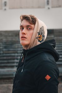 Portrait of young man standing against black background