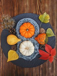 Background of autumn harvest of small orange different pumpkins on black plate close up. top view.