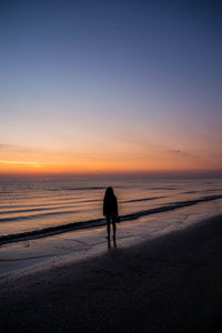 Silhouette man on beach against sky during sunset