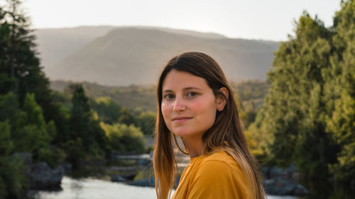 Portrait of young woman against trees