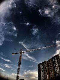 Low angle view of crane against sky in city