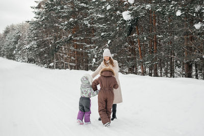 Mother with two daughters walks in a snowy forest on her day off. high quality photo