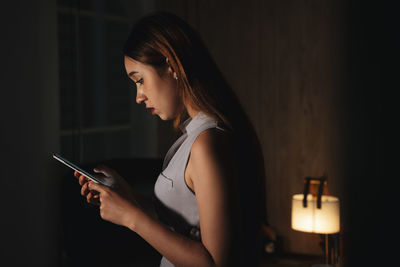 Cute girl using smart phone sitting at home