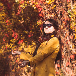 Woman standing by autumn leaves