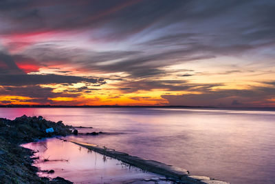 Scenic view of sea against dramatic sky during sunset