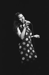 Close-up of woman holding hands against black background