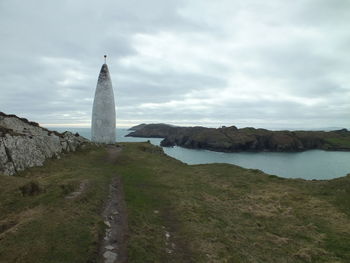 Baltimore beacon by sea against cloudy sky