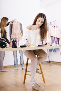 Female fashion designer writing at studio