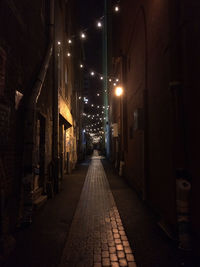 Empty alley amidst buildings at night