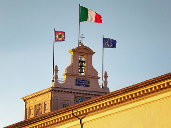 Flags on bell tower of quirinal palace against clear sky during sunset