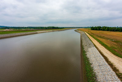 Empty road amidst field against sky