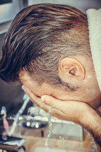 Close-up of man washing face at sink