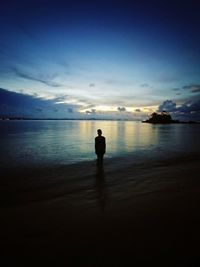 Silhouette man standing at beach against sky during sunset