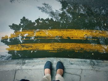 Low section of woman standing in front of puddle