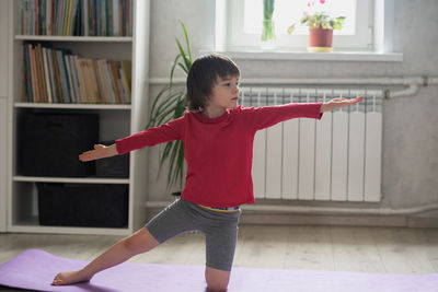 Child doing sports in the room at home. performs an exercise