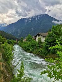 River amidst buildings and mountains against sky