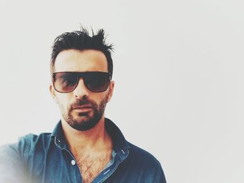 Portrait of young man wearing sunglasses against white background