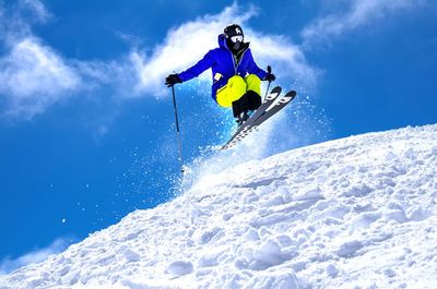 Low angle view of person skiing over snow covered field against sky