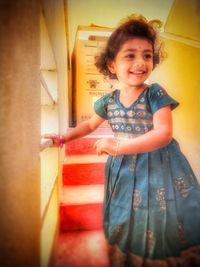 Portrait of smiling girl standing against wall