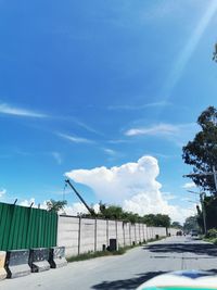 Road by buildings against blue sky