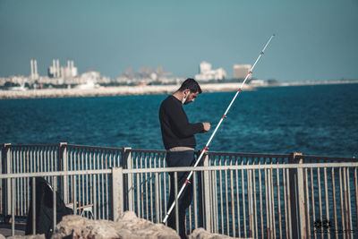 Man fishing in sea against sky