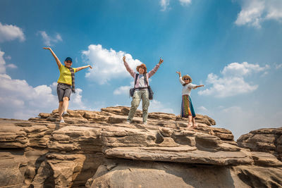 Low angle view of man standing on rock against sky