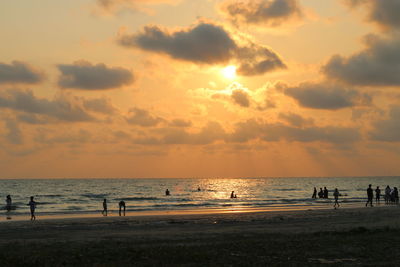 Silhouette people on beach against sky during sunset